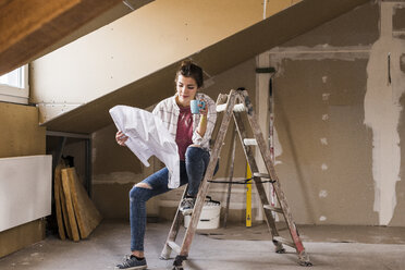 Junge Frau bei der Renovierung ihres neuen Hauses, mit Bauplan - UUF10078