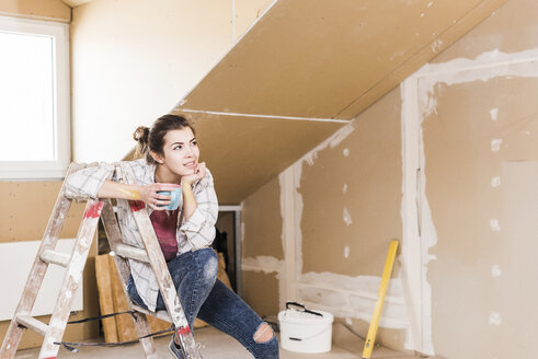 Junge Frau, die über die Renovierung ihres neuen Hauses nachdenkt - UUF10084