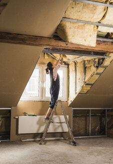 Young woman mounting insulation in her new home - UUF10090
