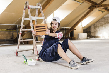 Junge Frau auf einer Baustelle sitzend, mit digitalem Tablet - UUF10092