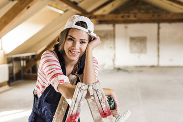 Young woman renovating her new home, holding paint roller - UUF10094