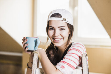 Junge Frau auf einer Baustelle mit einer Tasse Kaffee in der Hand - UUF10096