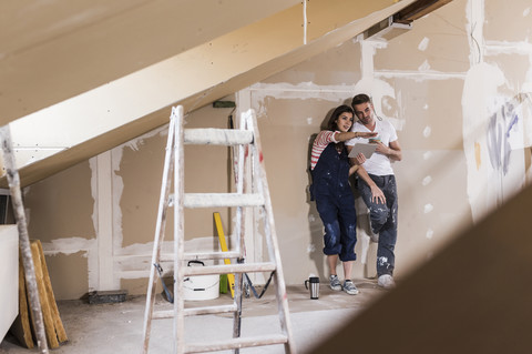 Junges Paar auf der Baustelle ihres neuen Hauses, mit digitalem Tablet, lizenzfreies Stockfoto