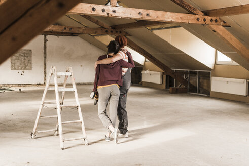 Young couple renovating their new home, looking at construction site - UUF10127