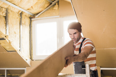 Young man checking plank on construction site - UUF10133