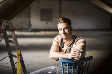 Young man sitting on construction site of his new home - UUF10141