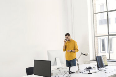 Junger Geschäftsmann im Büro beim Telefonieren - SBOF00305