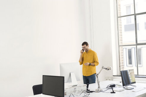 Junger Geschäftsmann im Büro beim Telefonieren - SBOF00305