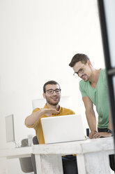 Zwei Geschäftsleute arbeiten zusammen im Büro und benutzen einen Laptop - SBOF00319