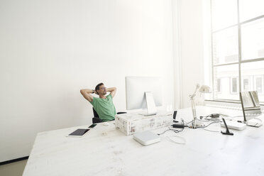 Young businessman in office relaxing at desk - SBOF00323