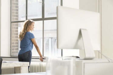 Casual businesswoman in office looking out of window - SBOF00335
