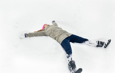 Junge Frau macht einen Schneeengel - MGOF03044