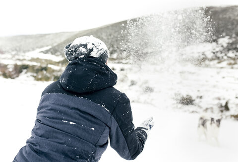 Junger Mann spielt mit seinem Hund im Schnee - MGOF03053