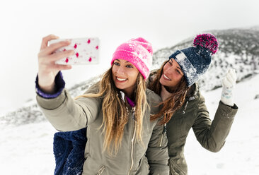 Zwei Freunde machen Selfies mit dem Smartphone im Schnee - MGOF03055