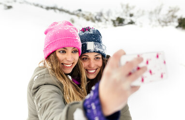 Zwei Freunde machen Selfies mit dem Smartphone im Schnee - MGOF03056