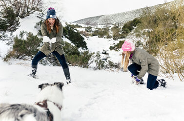 Zwei Freunde spielen mit ihrem Hund im Schnee - MGOF03062