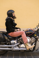 Bärtiger Biker mit Helm und Sonnenbrille auf seinem Motorrad sitzend - KKAF00492