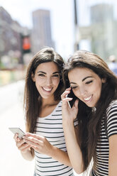 USA, New York City, zwei glückliche Zwillingsschwestern mit Handys in Manhattan - GIOF02181
