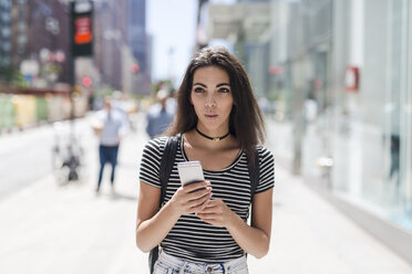 USA, New York City, young woman holding cell phone in Manhattan - GIOF02183