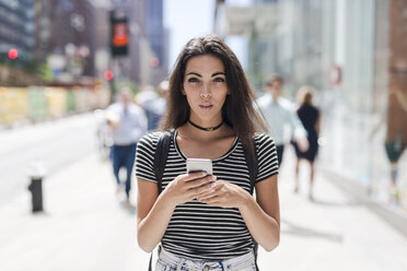 USA, New York City, young woman holding cell phone in Manhattan - GIOF02184