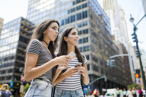 USA, New York City, two twin sisters with cell phones in Manhattan - GIOF02186