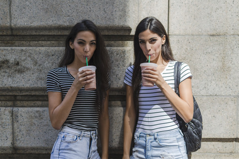 Zwei Zwillingsschwestern bei einem Getränk zum Mitnehmen, lizenzfreies Stockfoto