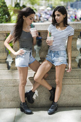 Zwei Zwillingsschwestern im Freien bei einem Getränk zum Mitnehmen - GIOF02206