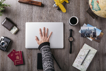 Overhead view of man's hand and travel items on table - JRFF01244