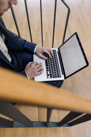 Geschäftsmann sitzt auf einer Treppe und benutzt einen Laptop, lizenzfreies Stockfoto