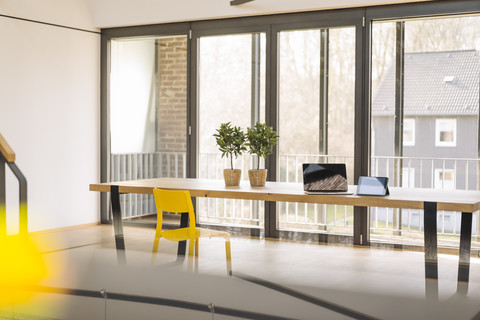 Empty loft office with laptop, tablet and potted plants on table stock photo