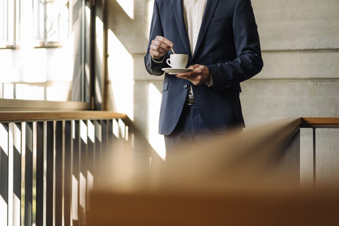 Geschäftsmann mit Tasse Kaffee im Treppenhaus, lizenzfreies Stockfoto