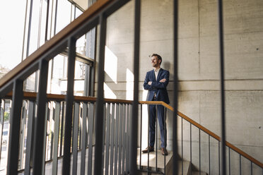 Smiling businessman standing in staircase - KNSF01171