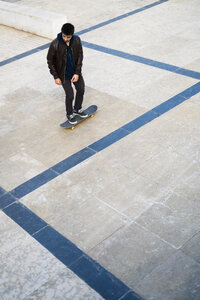 Junger Mann fährt Skateboard auf einem Platz - KKAF00503