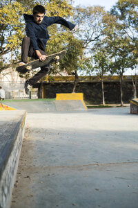 Junger Mann fährt auf einem Skateboard in einem Skatepark - KKAF00509