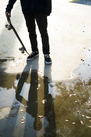 Skateboarder in einem Skatepark, der sich in einer Pfütze spiegelt, lizenzfreies Stockfoto