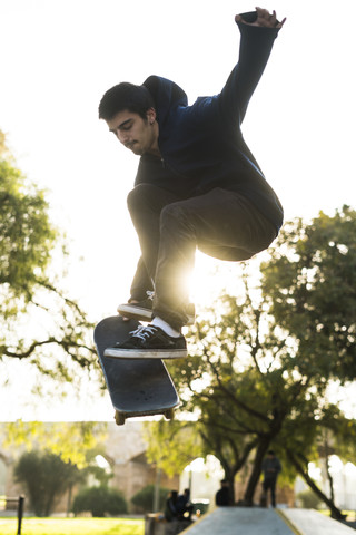 Junger Mann mit Skateboard springt in die Luft, lizenzfreies Stockfoto