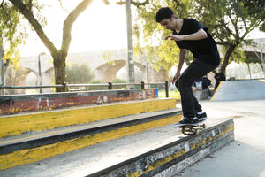 Junger Mann fährt auf einem Skateboard in einem Skatepark - KKAF00516
