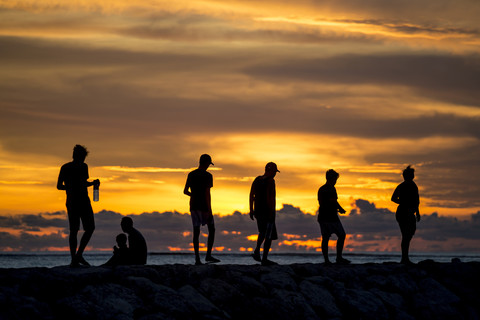 Indonesien, Bali, Menschen bei Sonnenuntergang an der Meeresküste, lizenzfreies Stockfoto