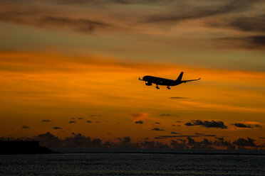 Indonesien, Bali, Flugzeug am Himmel und Sonnenuntergang über dem Meer - KNTF00748