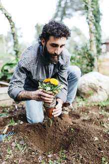 Mann pflanzt Blumen in seinem Garten - JRFF01260