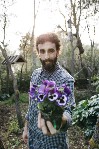 Mann hält eine Blume im Garten, lizenzfreies Stockfoto