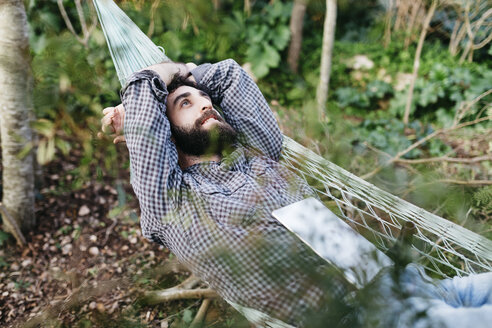 Man lying relaxed in hammock with a tablet - JRFF01288