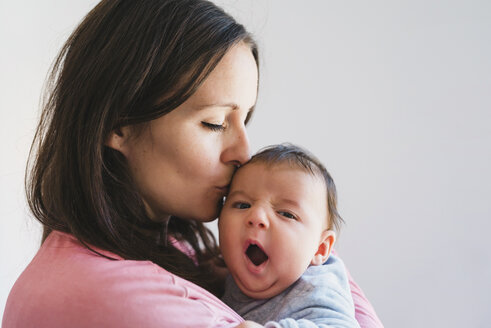 Frau hält und küsst ein gähnendes Baby - GEMF01523
