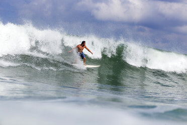 Indonesien, Bali, Mann surft auf einer Welle - KNTF00749