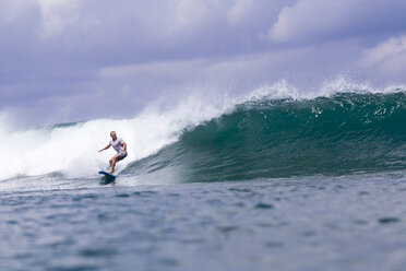 Indonesien, Bali, Mann surft auf einer Welle - KNTF00751