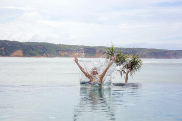 Indonesien, Insel Lombok, Frau springt in Infinity-Pool - KNTF00757