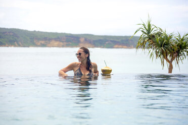 Indonesien, Insel Lombok, lächelnde Frau im Infinity-Pool - KNTF00760