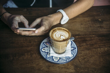 Woman using cell phone in a cafe - KNTF00763