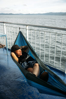 Indonesien, Insel Lombok, Frau in Hängematte auf Schiffsdeck liegend - KNTF00771