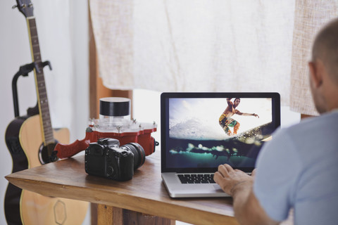 Mann arbeitet an einer Fotografie auf einem Laptop-Display, lizenzfreies Stockfoto